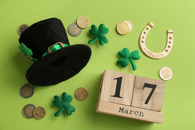 Leprechaun's hat, block calendar and St. Patrick's day decor on green background, flat lay