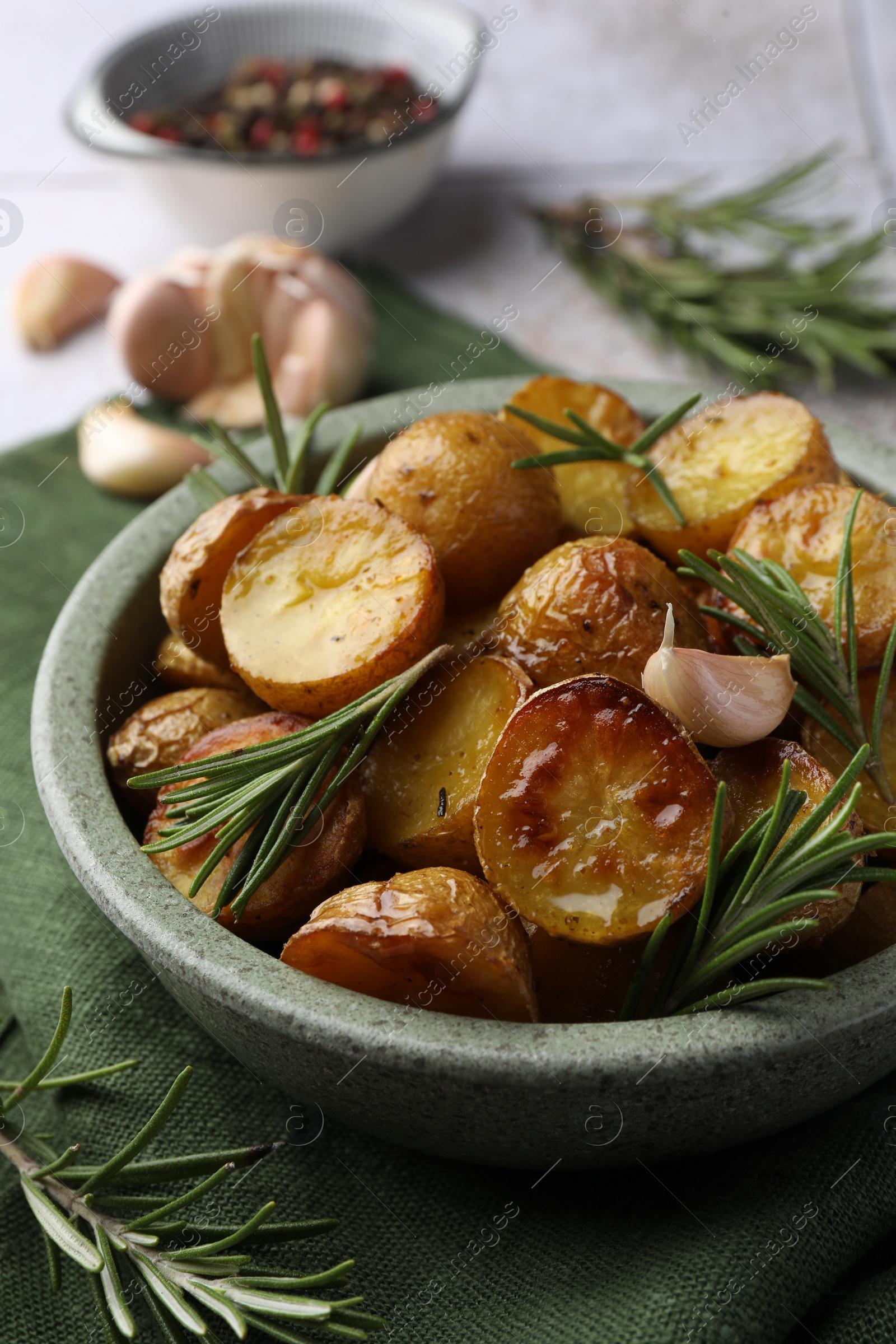 Photo of Tasty baked potato and aromatic rosemary in bowl on table, closeup