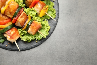 Delicious chicken shish kebabs with vegetables on grey table, top view. Space for text