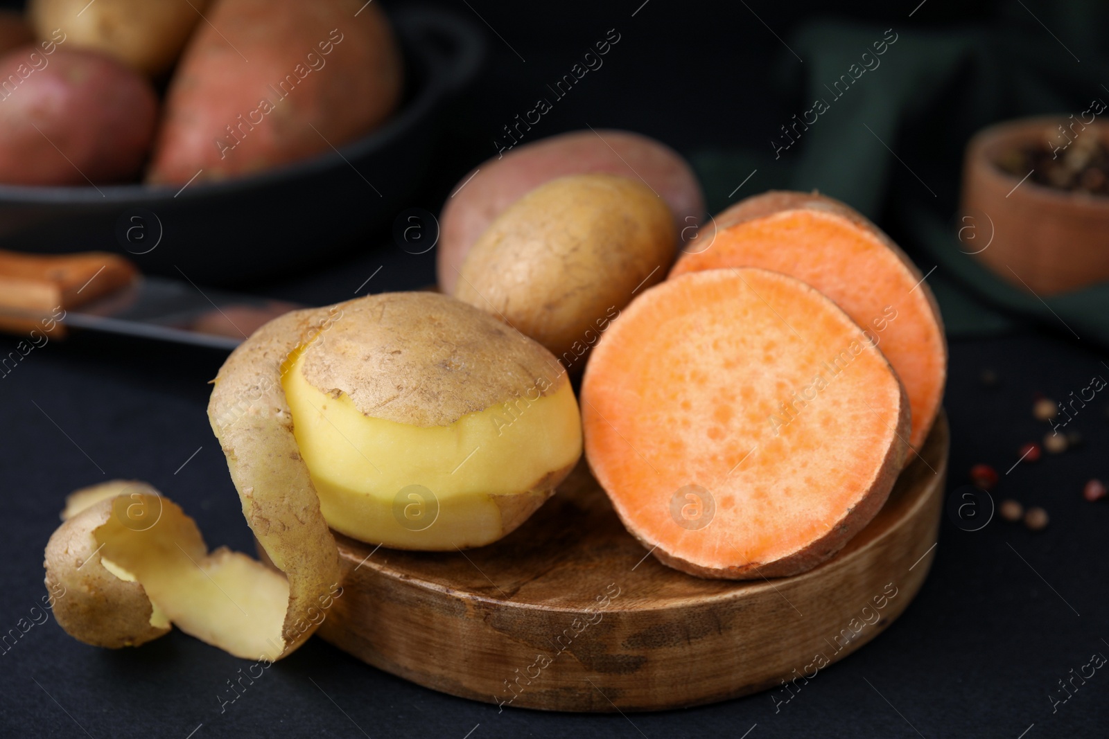 Photo of Wooden board with fresh potatoes on black table