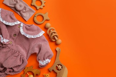 Flat lay composition with baby clothes and accessories on orange background, space for text