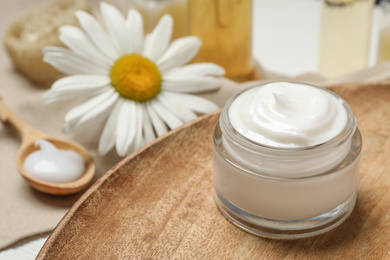 Photo of Cosmetic cream and chamomile on table, closeup