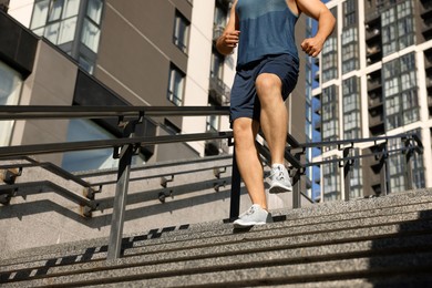 Man running down stairs outdoors on sunny day, closeup. Space for text