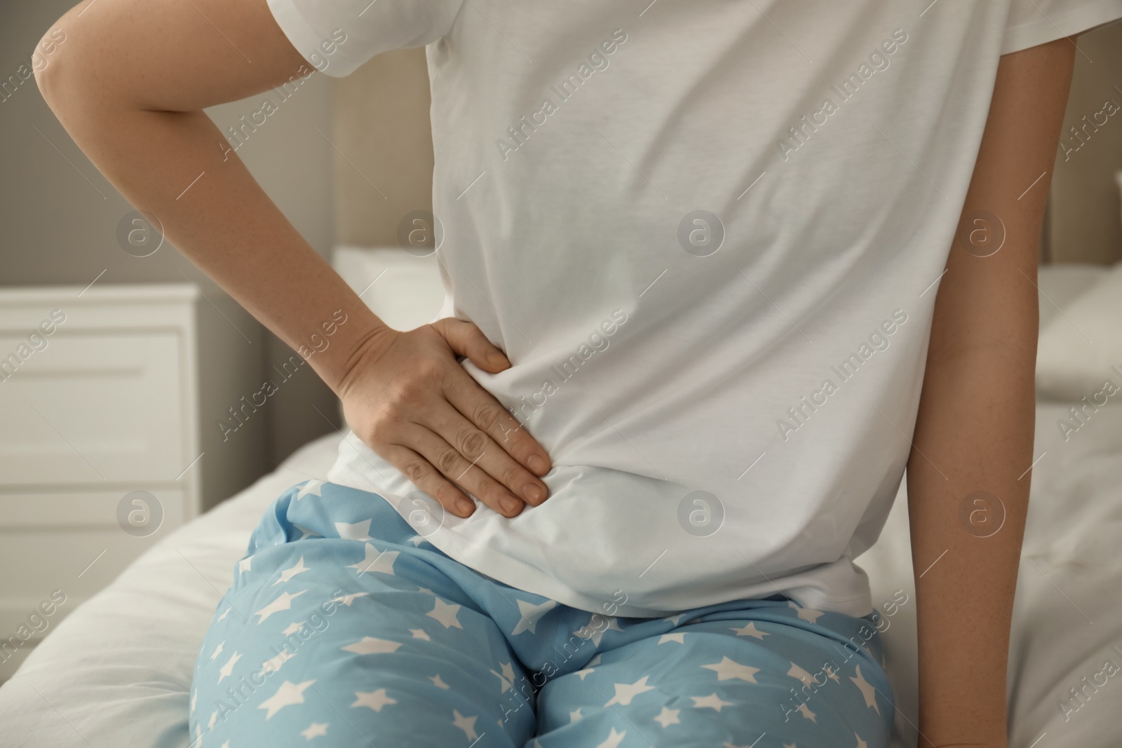 Photo of Woman suffering from appendicitis inflammation on bed at home, closeup