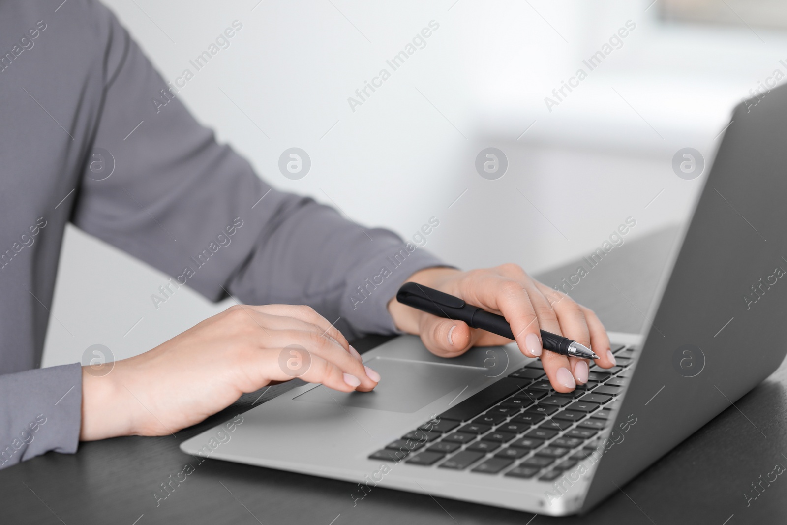 Photo of Woman working on laptop at table, closeup. Electronic document management