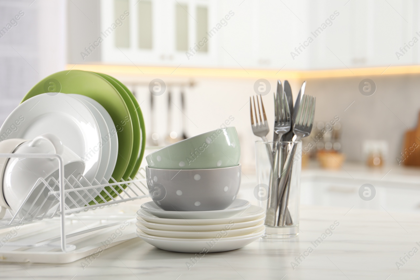 Photo of Many different clean dishware, cup and cutlery on white marble table in kitchen