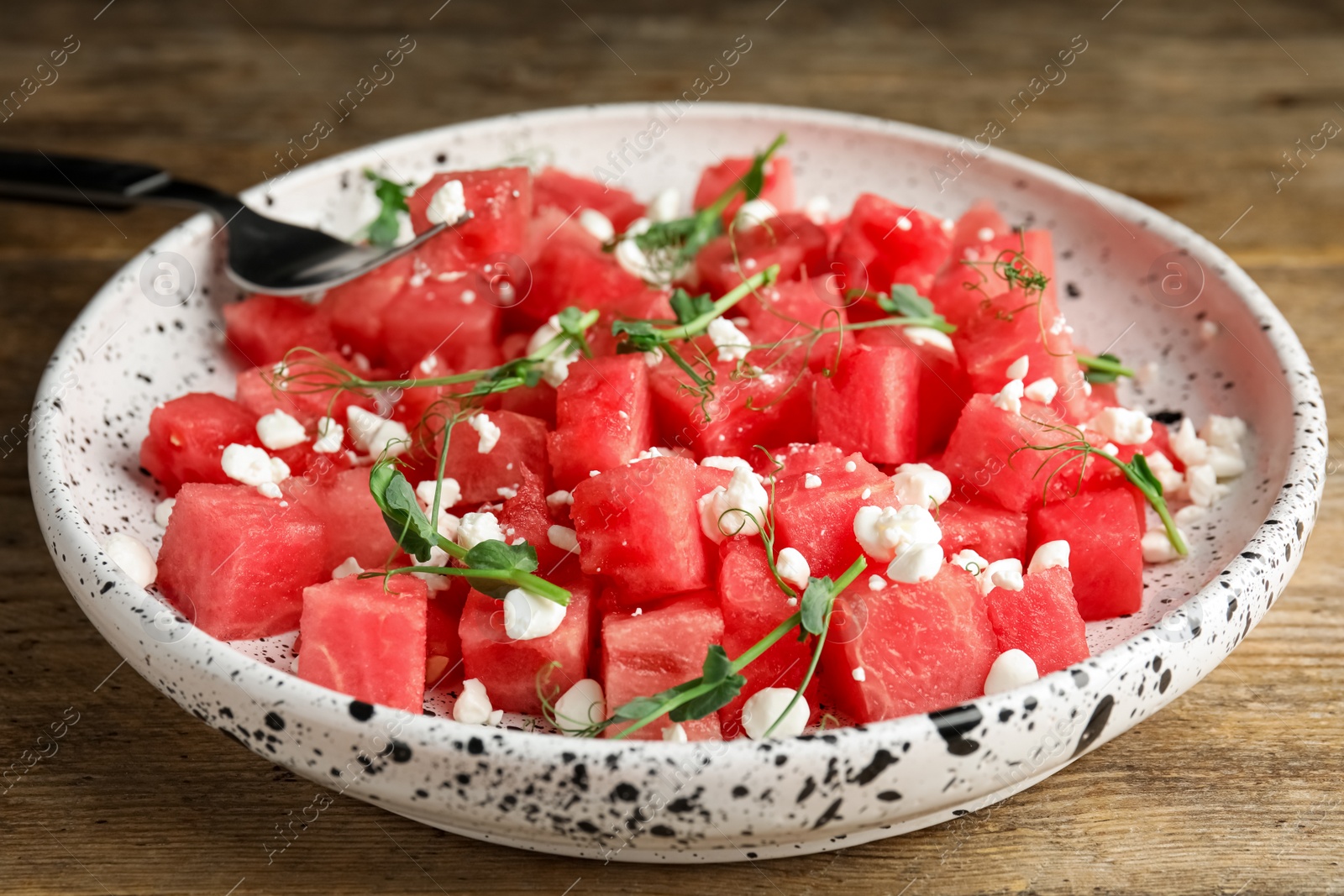 Photo of Delicious salad with watermelon served on wooden table, closeup