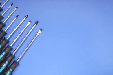 Photo of Set of screwdrivers on blue background, flat lay. Space for text