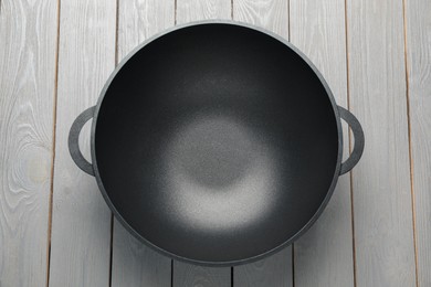 Photo of Empty iron wok on grey wooden table, top view. Chinese cookware