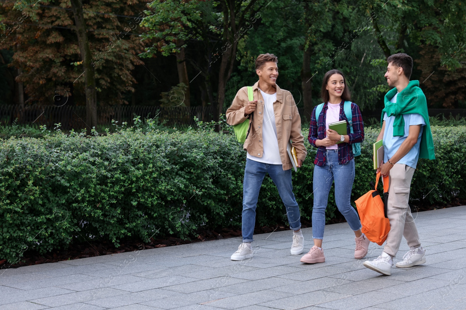 Photo of Happy young students walking together in park