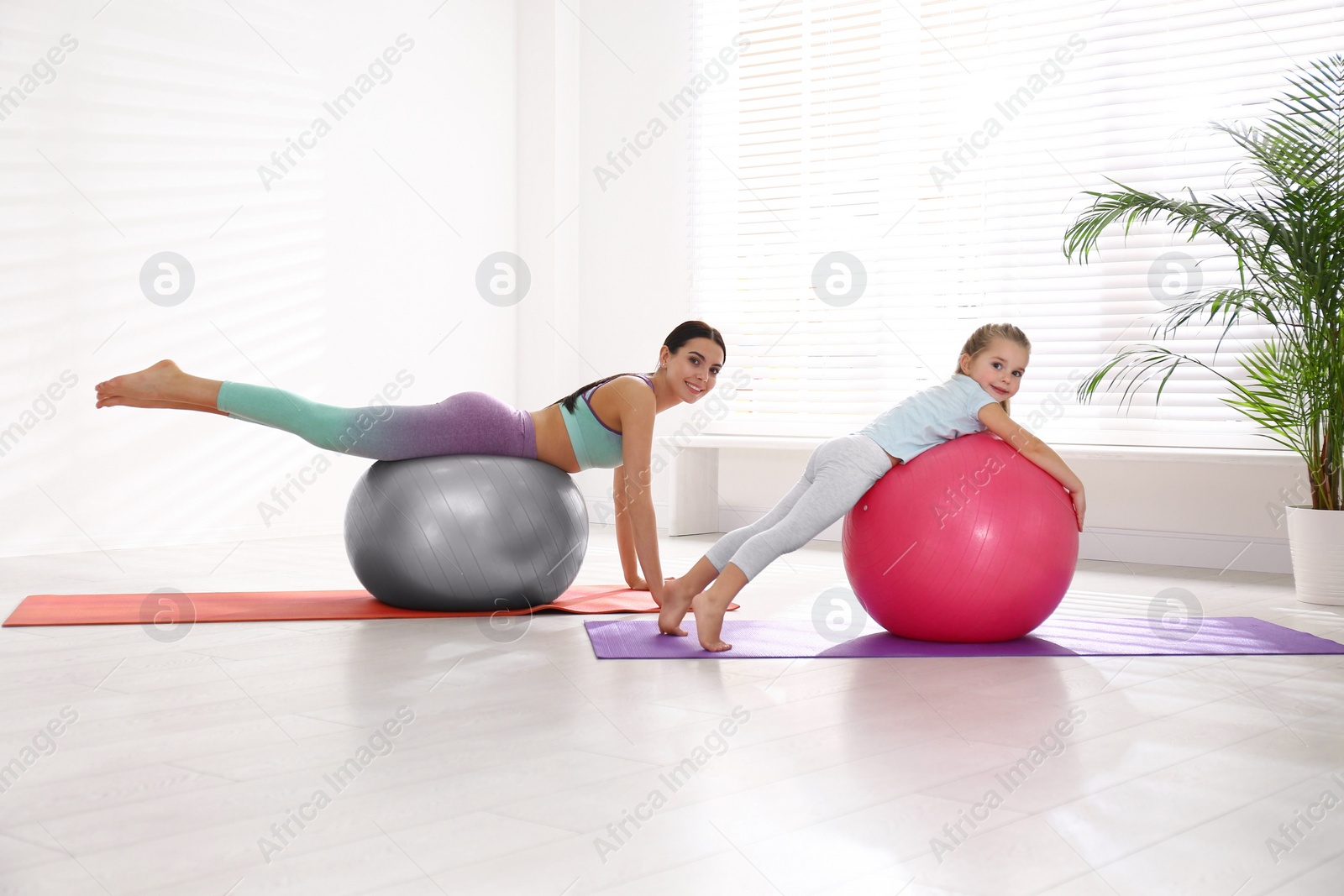 Photo of Woman and daughter doing exercise with fitness balls at home