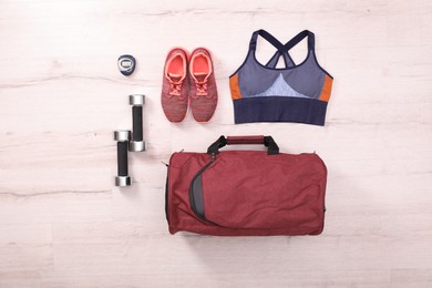 Photo of Red bag and sports accessories on floor, flat lay