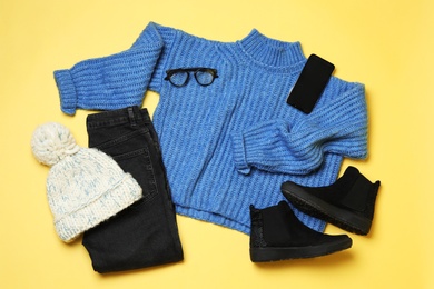 Photo of Flat lay composition with winter clothes and boots on yellow background