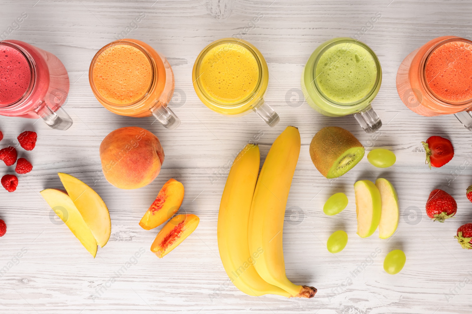 Photo of Many different tasty smoothies and ingredients on white wooden table, flat lay