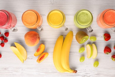 Many different tasty smoothies and ingredients on white wooden table, flat lay