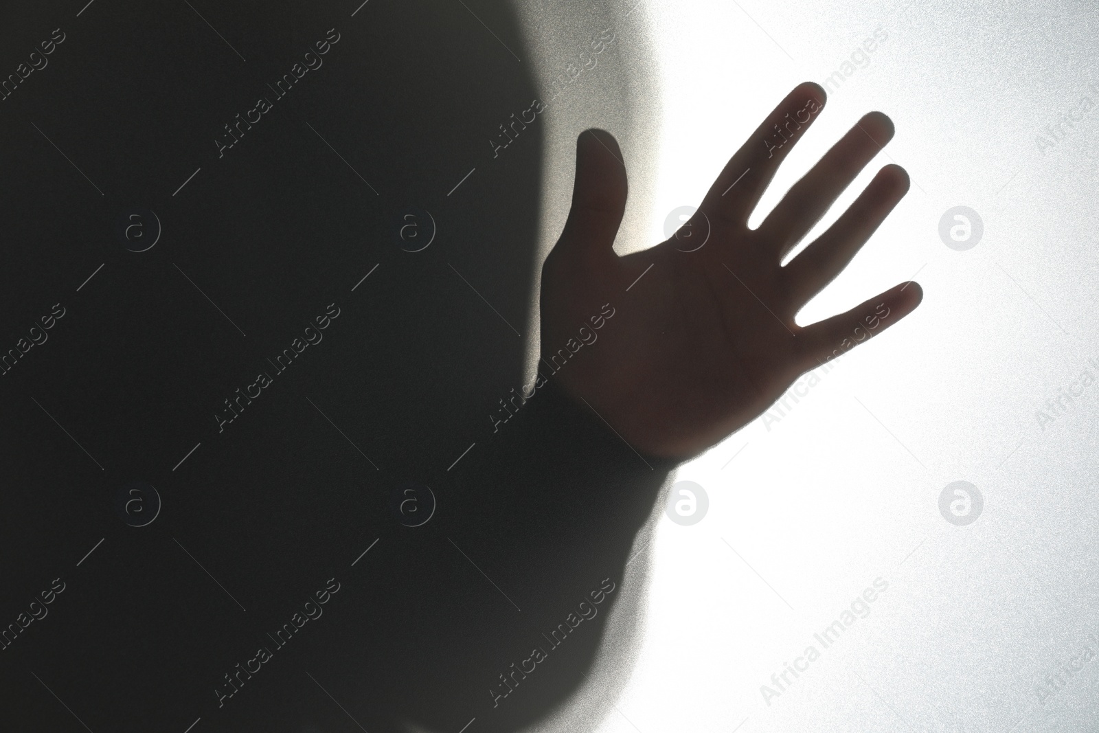 Photo of Silhouette of ghost behind glass against white background, closeup