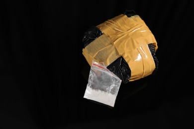 Photo of Smuggling and drug trafficking. Packages with narcotics on black surface, space for text