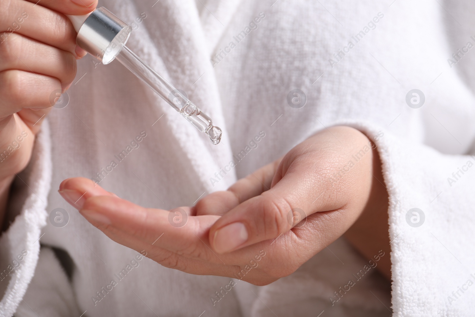 Photo of Woman applying cosmetic serum onto hand, closeup