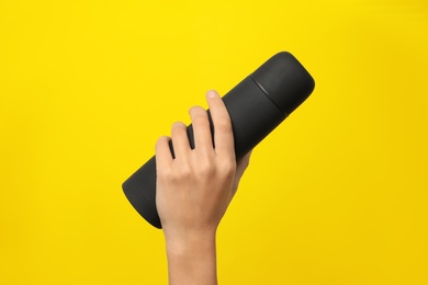 Photo of Woman holding modern black thermos on yellow background, closeup