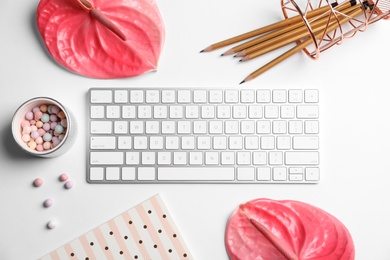 Creative flat lay composition with tropical flowers, stationery and computer keyboard on white background