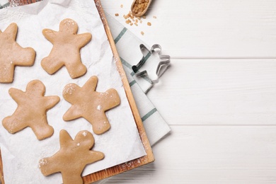 Photo of Flat lay composition with homemade gingerbread man cookies on white wooden table, space for text