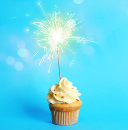 Image of Birthday cupcake with sparkler on light blue background