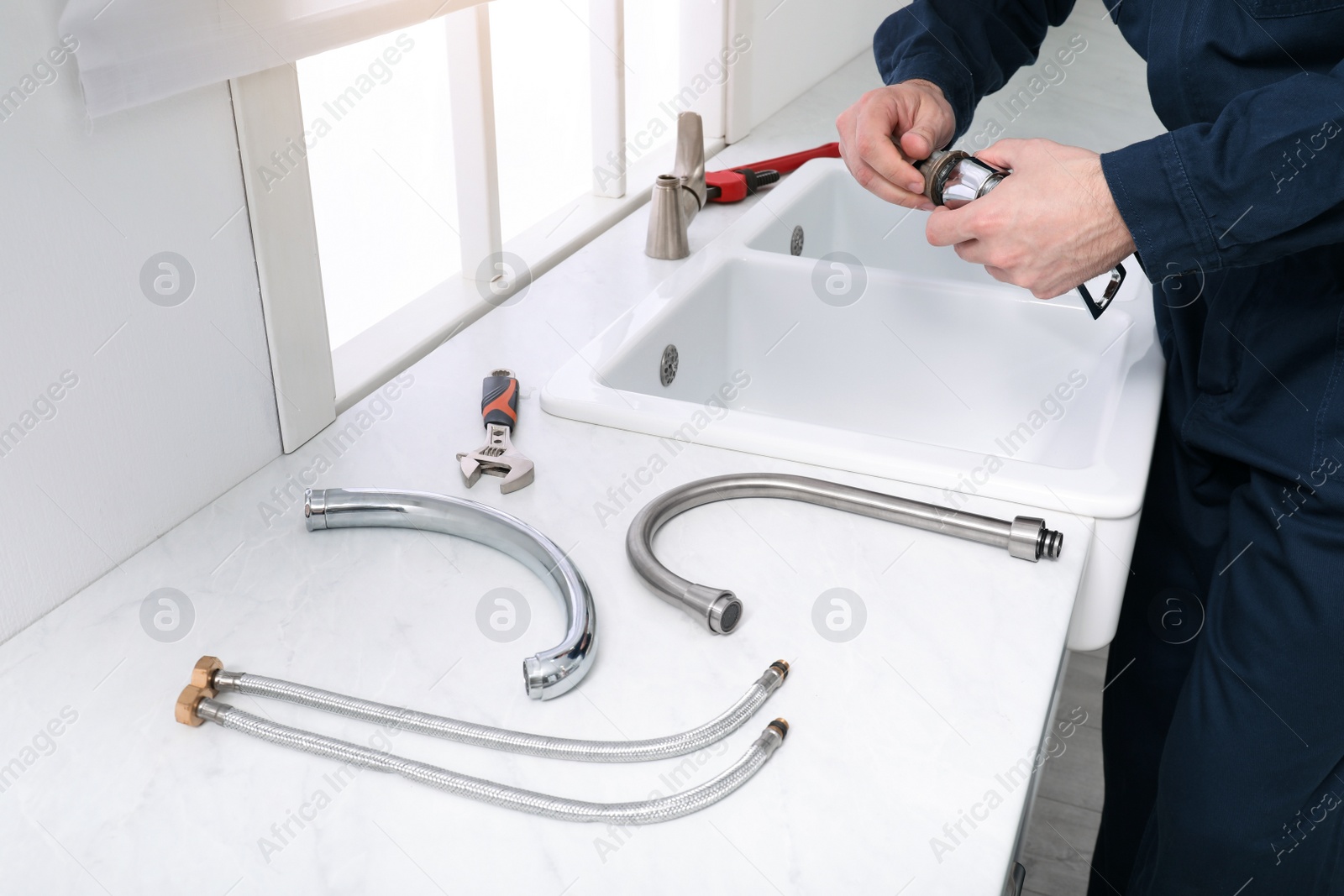 Photo of Professional plumber fixing water tap in kitchen, closeup