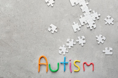 Photo of Word "Autism" and puzzle pieces on light background, flat lay