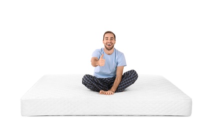 Photo of Young man sitting on mattress against white background