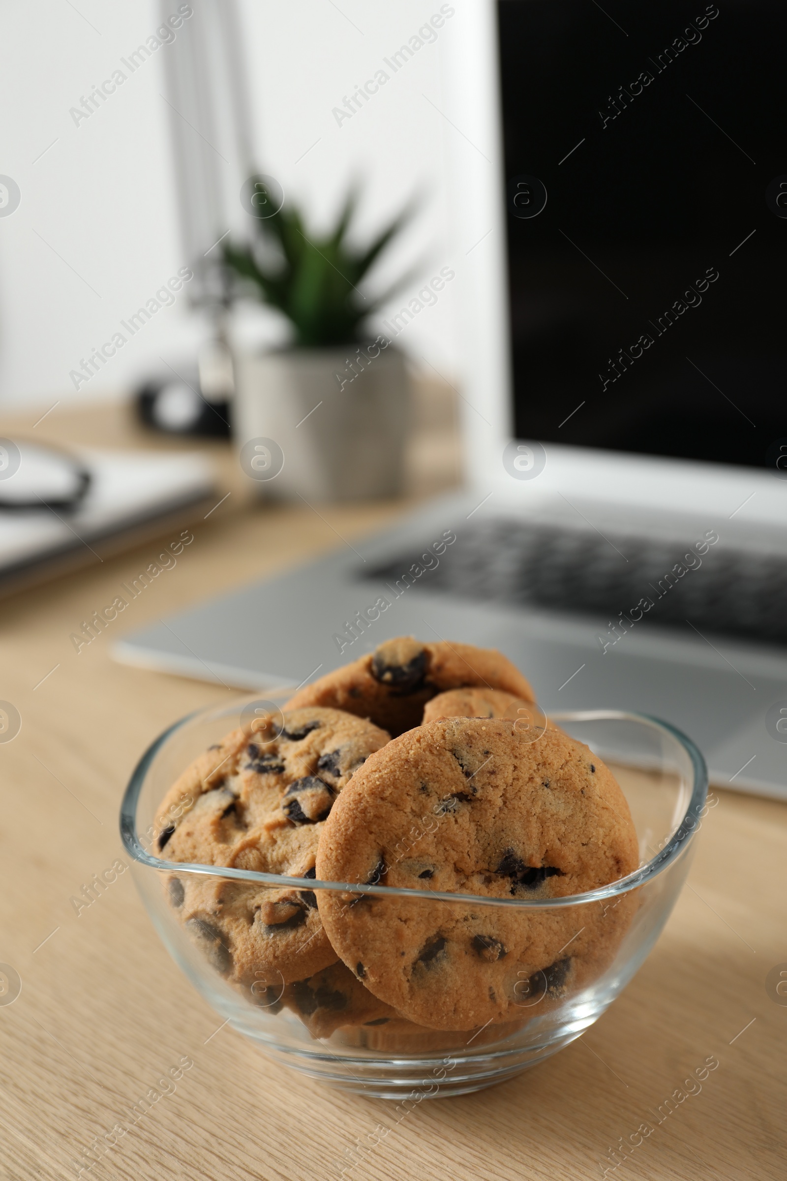 Photo of Chocolate chip cookies on wooden table at workplace