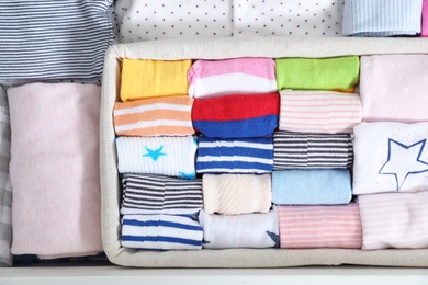 Photo of Basket with child socks among other clothes, top view. Baby wardrobe