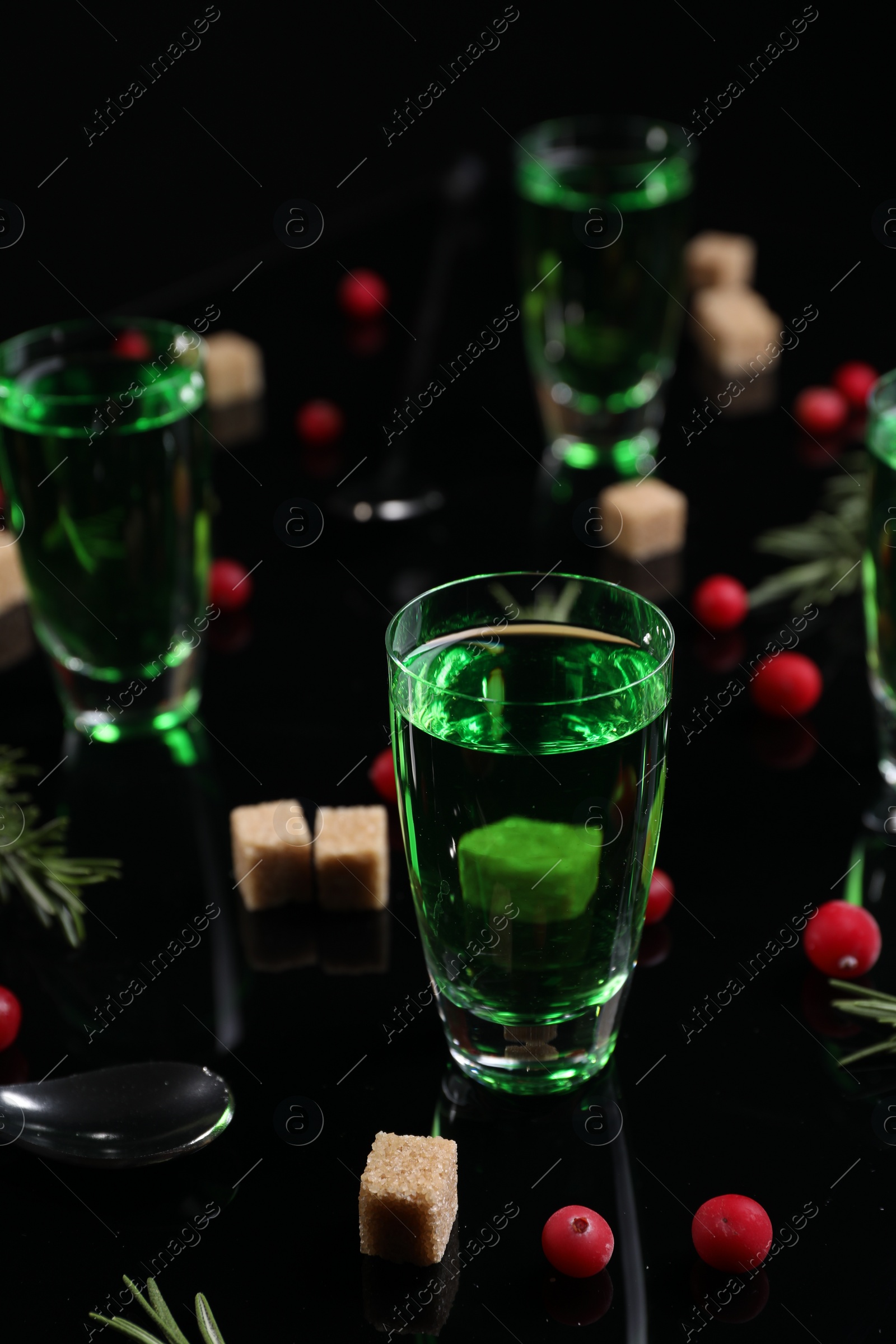 Photo of Absinthe in shot glasses, cranberries, rosemary and brown sugar on mirror table. Alcoholic drink