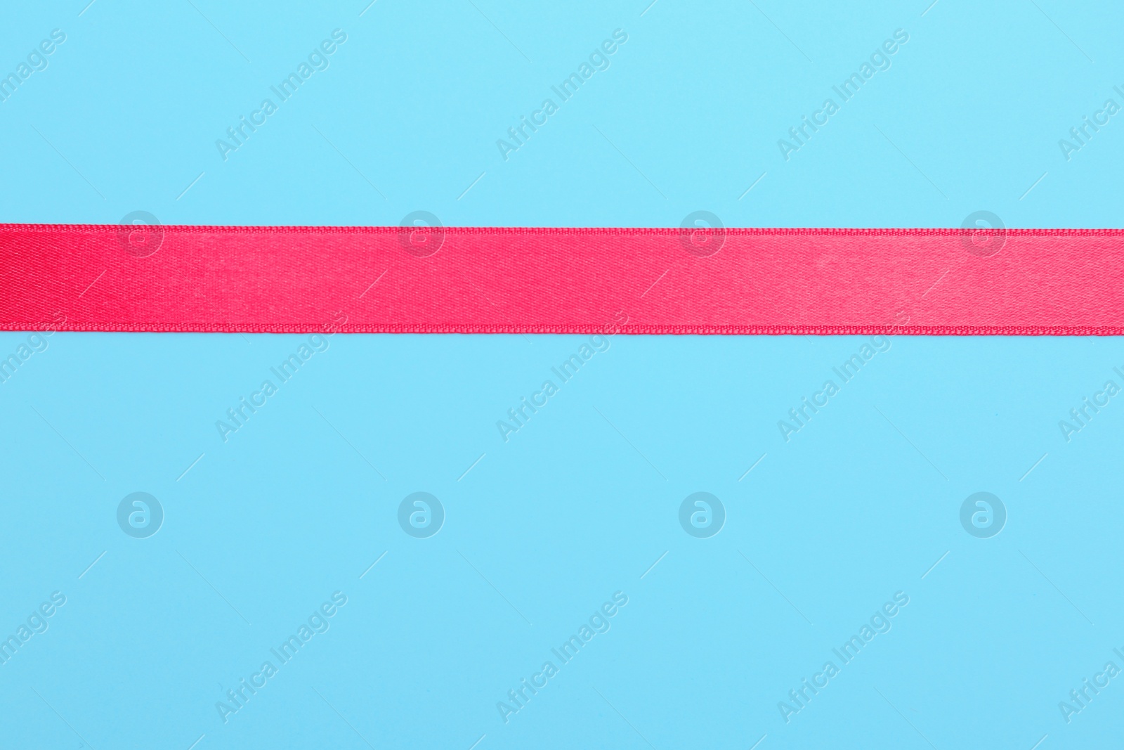 Photo of Simple pink ribbon on color background, top view