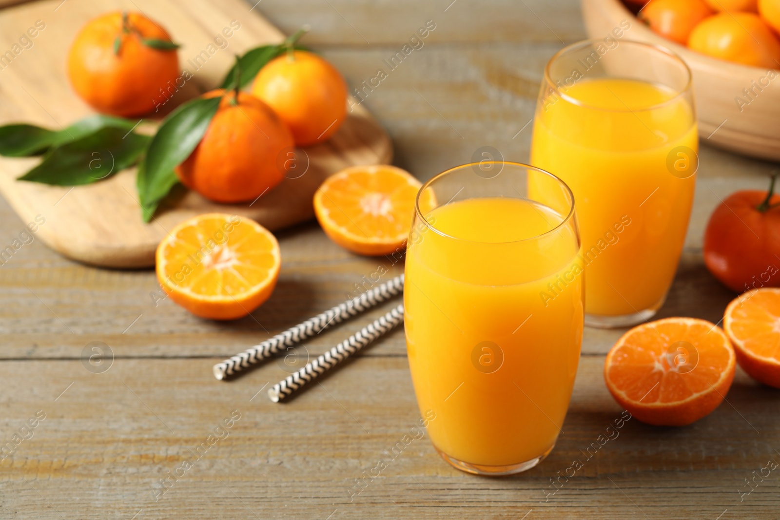 Photo of Glasses of fresh tangerine juice and fruits on wooden table. Space for text