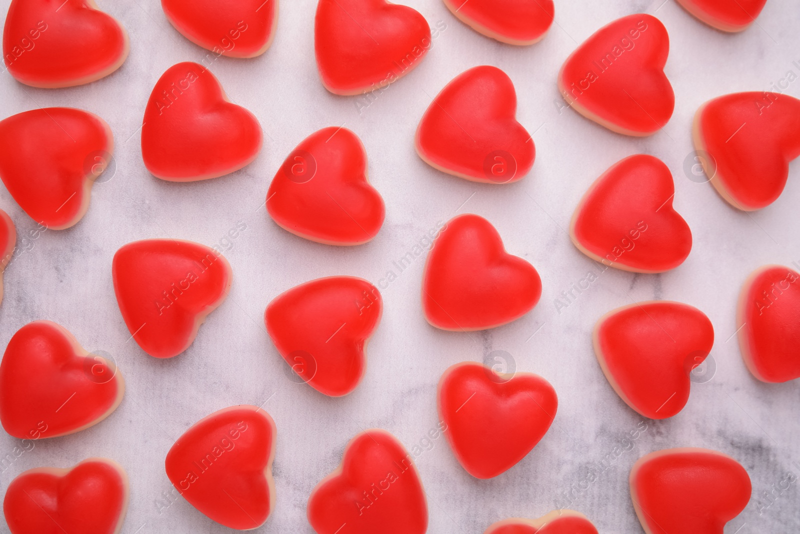 Photo of Delicious heart shaped jelly candies on white marble table, flat lay