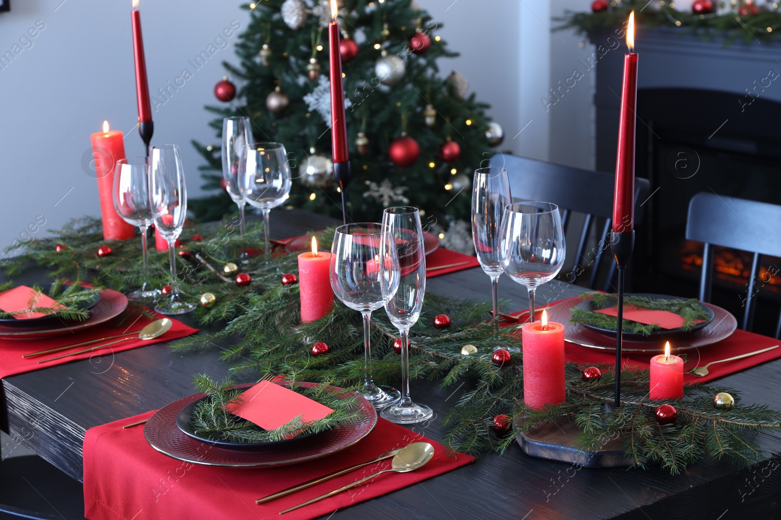 Photo of Elegant Christmas table setting with dishware and burning candles in festively decorated room