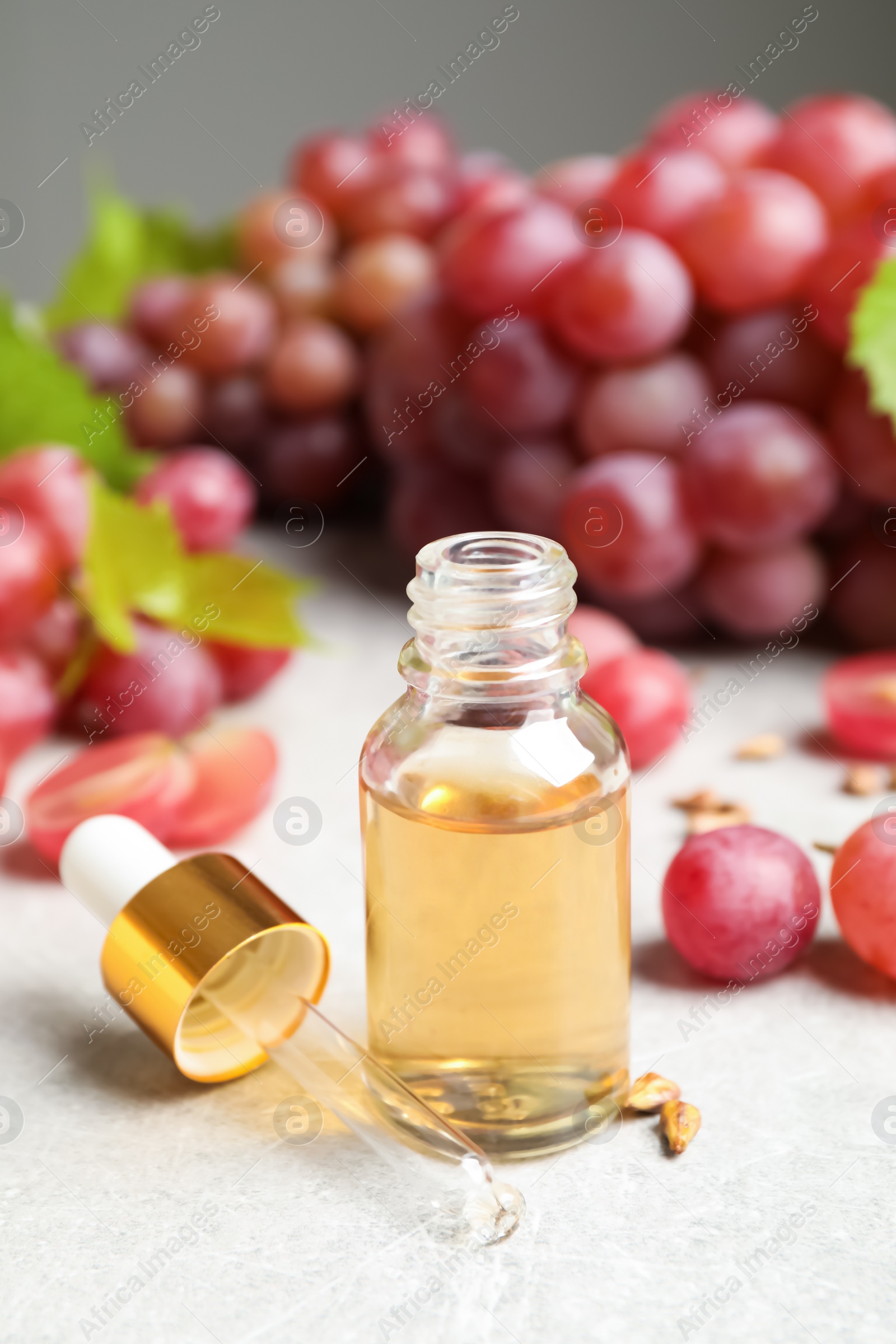 Photo of Natural grape seed oil and fresh berries on light table. Organic cosmetic