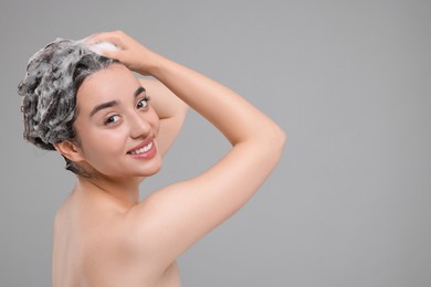 Photo of Beautiful happy woman washing hair on grey background. Space for text