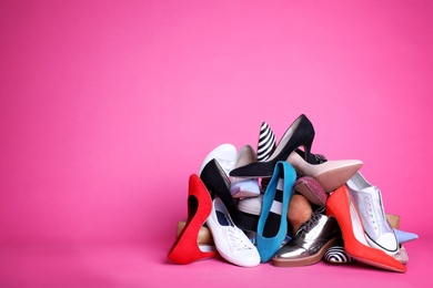 Photo of Heap of different shoes on color background. Space for text