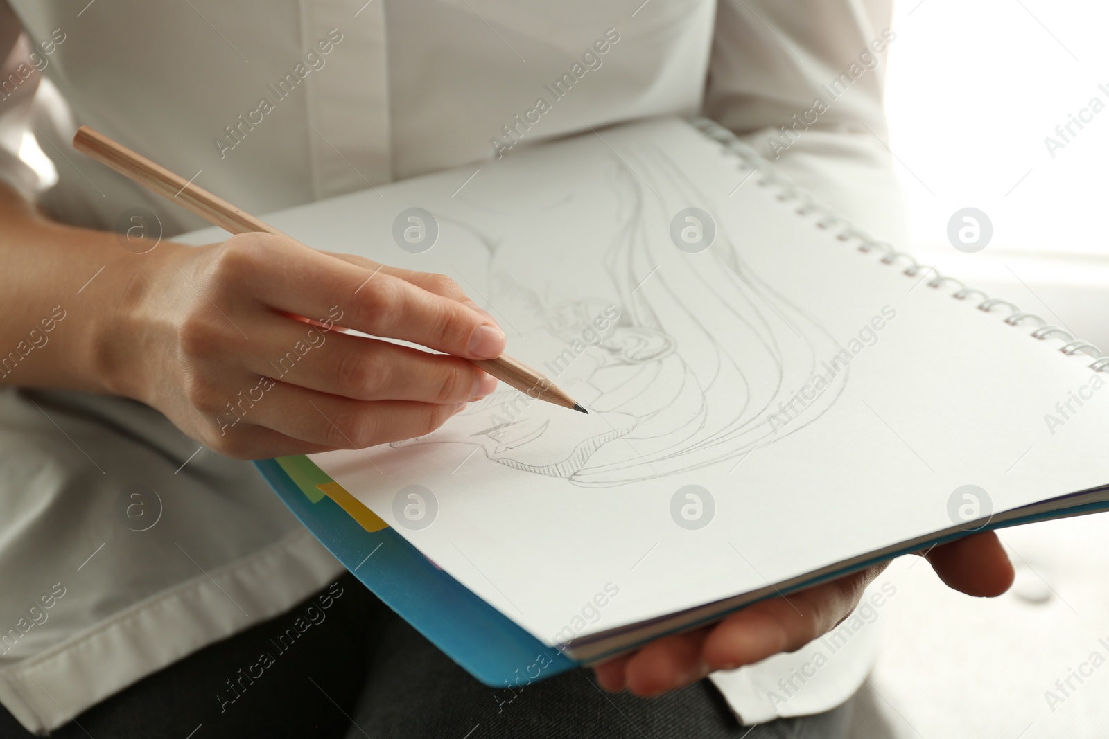 Photo of Woman drawing girl's portrait with pencil in notepad, closeup