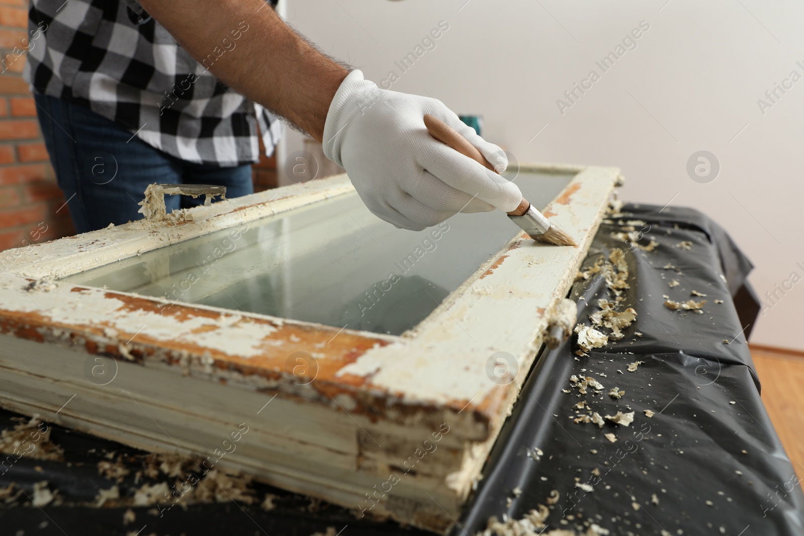 Photo of Man repairing old damaged window at table indoors, closeup