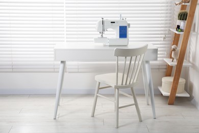 Photo of Sewing machine on white desk near chair indoors