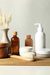 Different bath accessories and spikes on white table against grey background