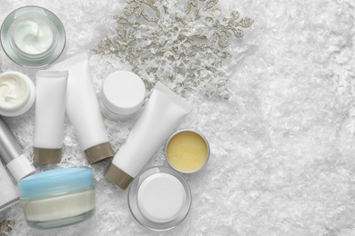 Photo of Set of cosmetic products on decorative snow, flat lay with space for text. Winter care