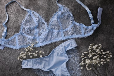 Photo of Elegant light blue women's underwear and gypsophila flowers on grey background, flat lay