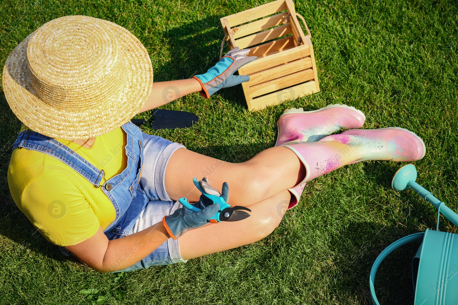 Photo of Young woman and gardening tools on green grass, above view