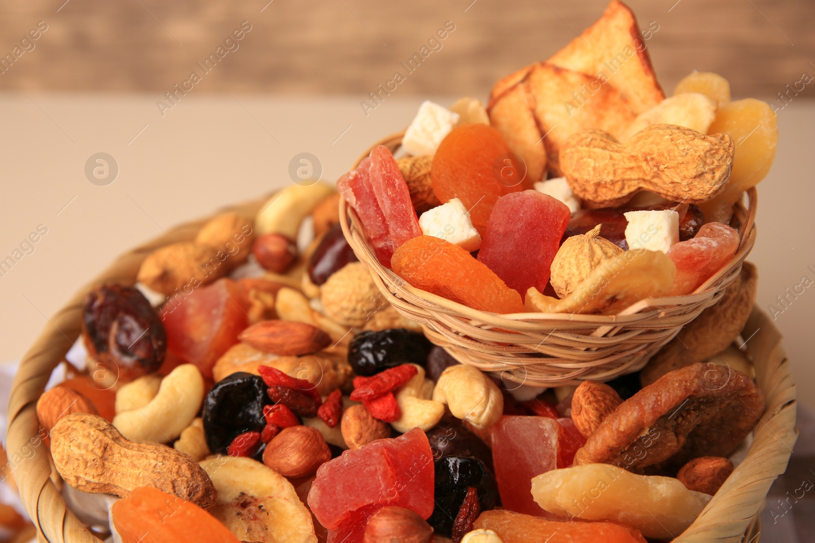 Photo of Wicker baskets with mixed dried fruits and nuts on blurred background, closeup