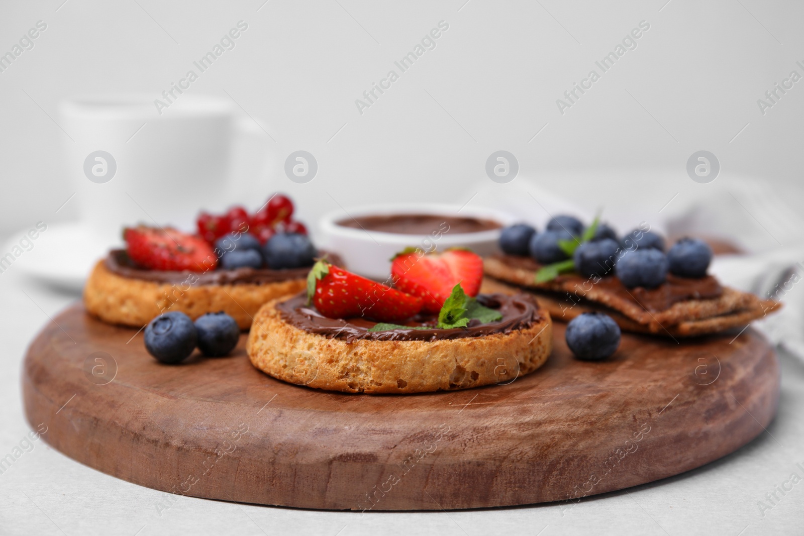 Photo of Tasty organic rusks and crispbreads with toppings on light grey table, closeup