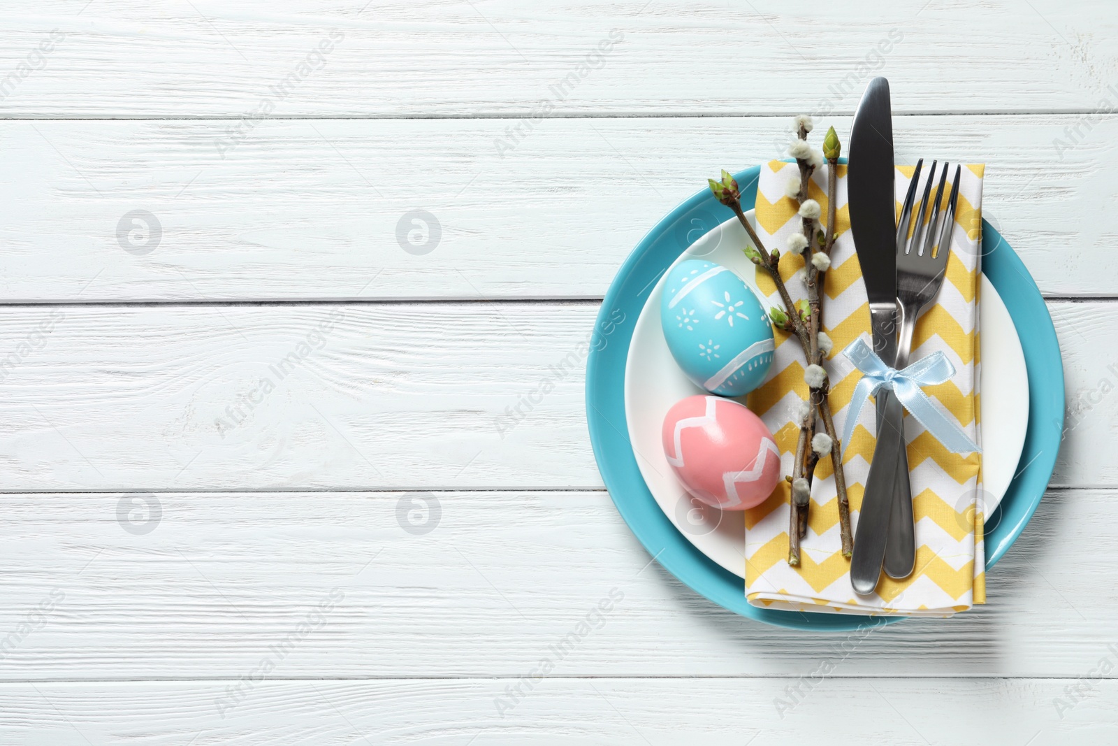 Photo of Festive Easter table setting with painted eggs on wooden background, top view. Space for text