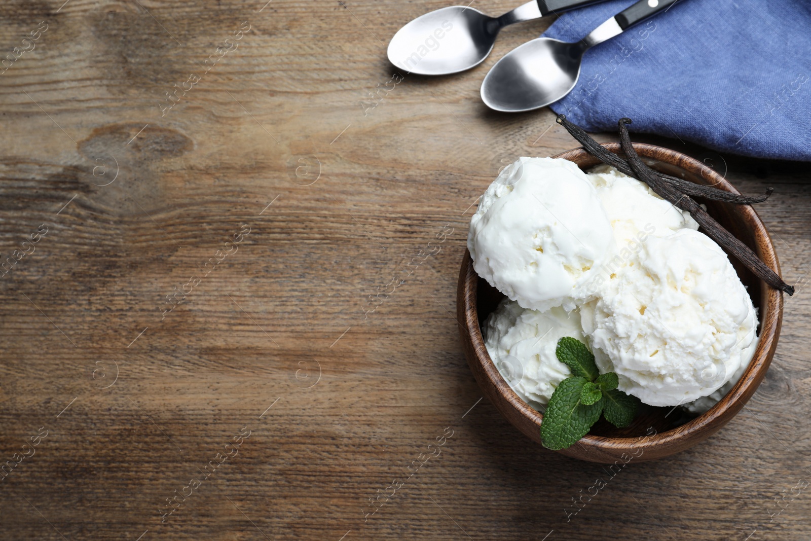 Photo of Yummy vanilla ice cream served on wooden table, flat lay. Space for text